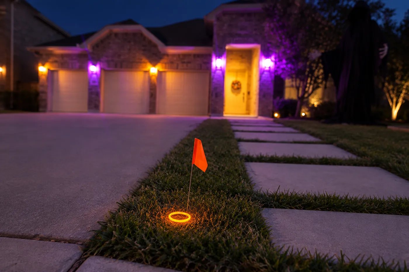 Orange flag and glowing orange ring in the grass beside a front walkway at dusk